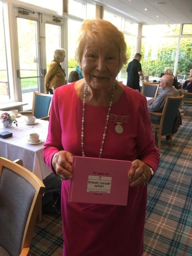 Margaret holding a photobook at an event celebrating 25 years of Breast Cancer Research Action Group