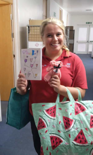 A Play Team member holding the thank you card and arts & craft supplies Olivia donated